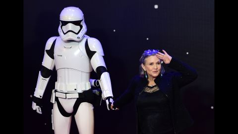 Fisher salutes as she poses with a storm trooper at the European premiere of "Star Wars: The Force Awakens" in central London on December 16, 2015.