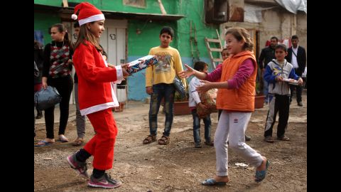 Chloe, a Lebanese Christian teenager dressed as Santa Claus, hands a gift to a Syrian refugee on December 24, during a gift distribution organized by the Maronite congregation "Mission de Vie" in a slum in the town of Dbayeh, north of Beirut.