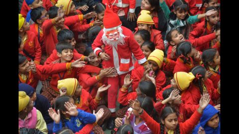 An Indian schoolboy wearing a Santa Claus outfit is surrounded by classmates as he gives out sweets during Christmas celebrations at a school in Amritsar on Christmas Eve.