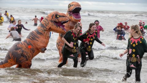 Participants dressed as dinosaurs and in festive clothing join in the Christmas Day 'Fancy Dress' swim in Dorset, England, to raise money for charity.