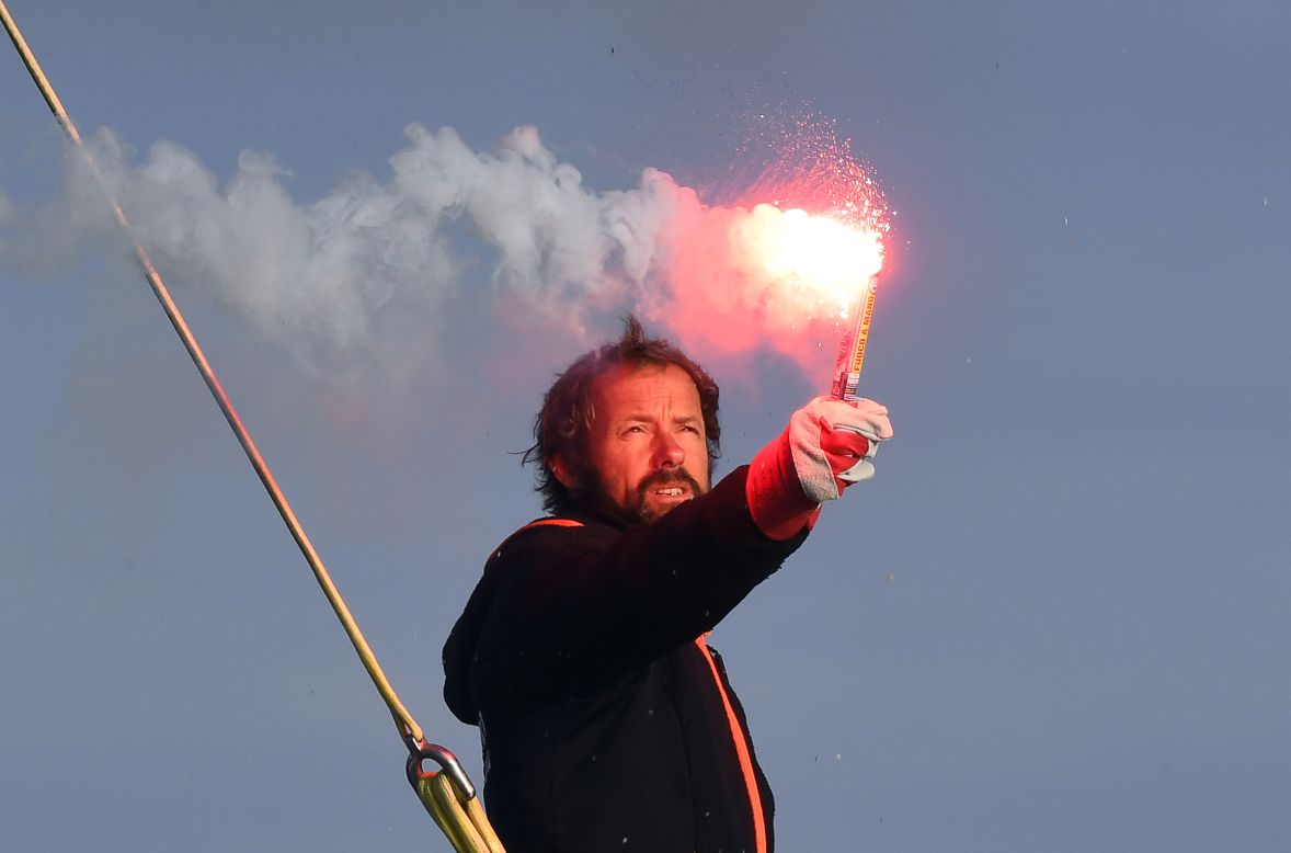 Thomas Coville holds a burning flare onboard his "Sodebo Ultim'" multihull as he arrives in the port of Brest, western France, on December 26, 2016, after beating the record in solo nonstop, round-the-world sailing.