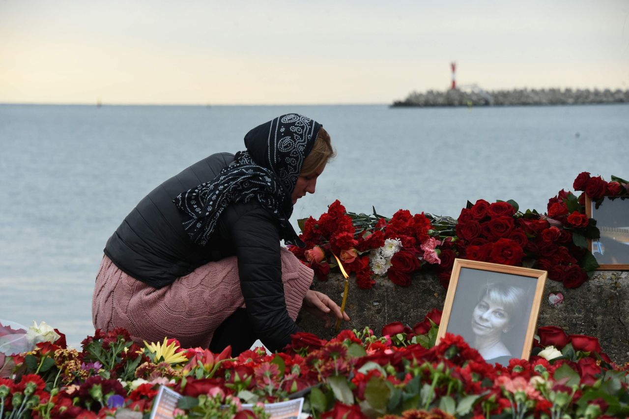 A woman lights a candle Tuesday next to makeshift memorial in Sochi, Russia, for  Russian activist Elizaveta Glinka, who was killed in the crash. Also presumed dead were nine journalists and more than 60 members of the Russian army's official choir, the Alexandrov Ensemble.