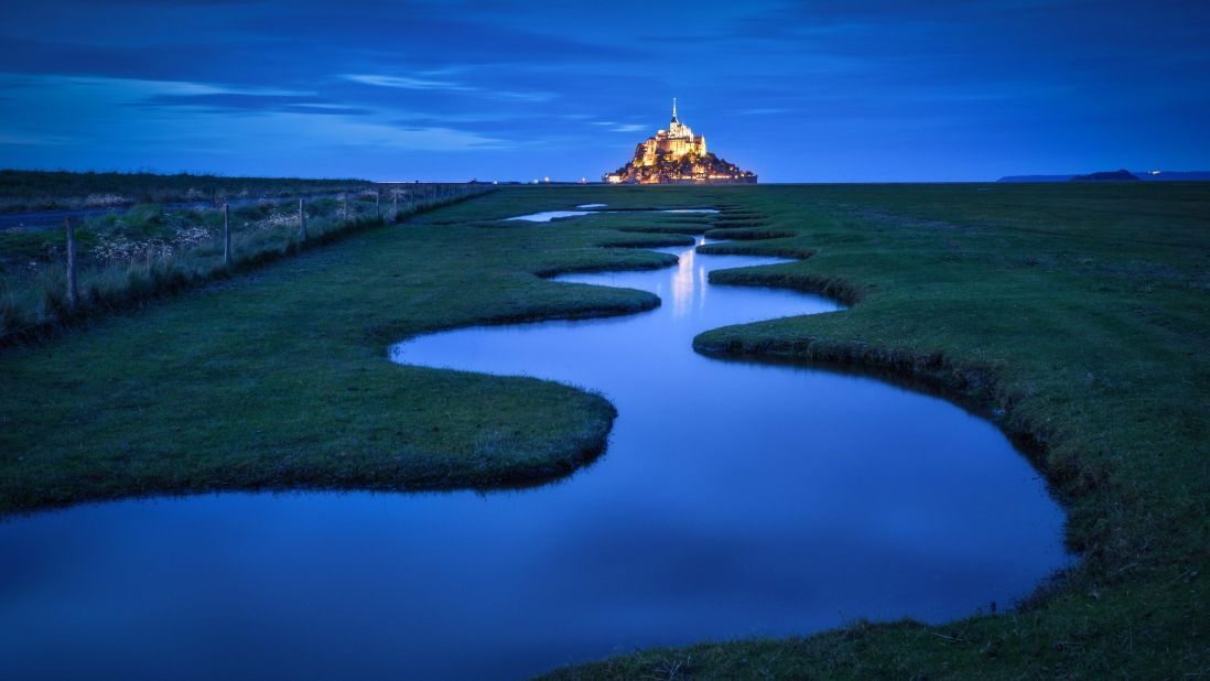 The abbey at Mont Saint Michel, an island community in Normandy, France, is a UNESCO World Heritage Site. About 40 to 50 people live in the medieval walled city, which hosts more than a million tourists each year. High tide turns the abbey into an island. 