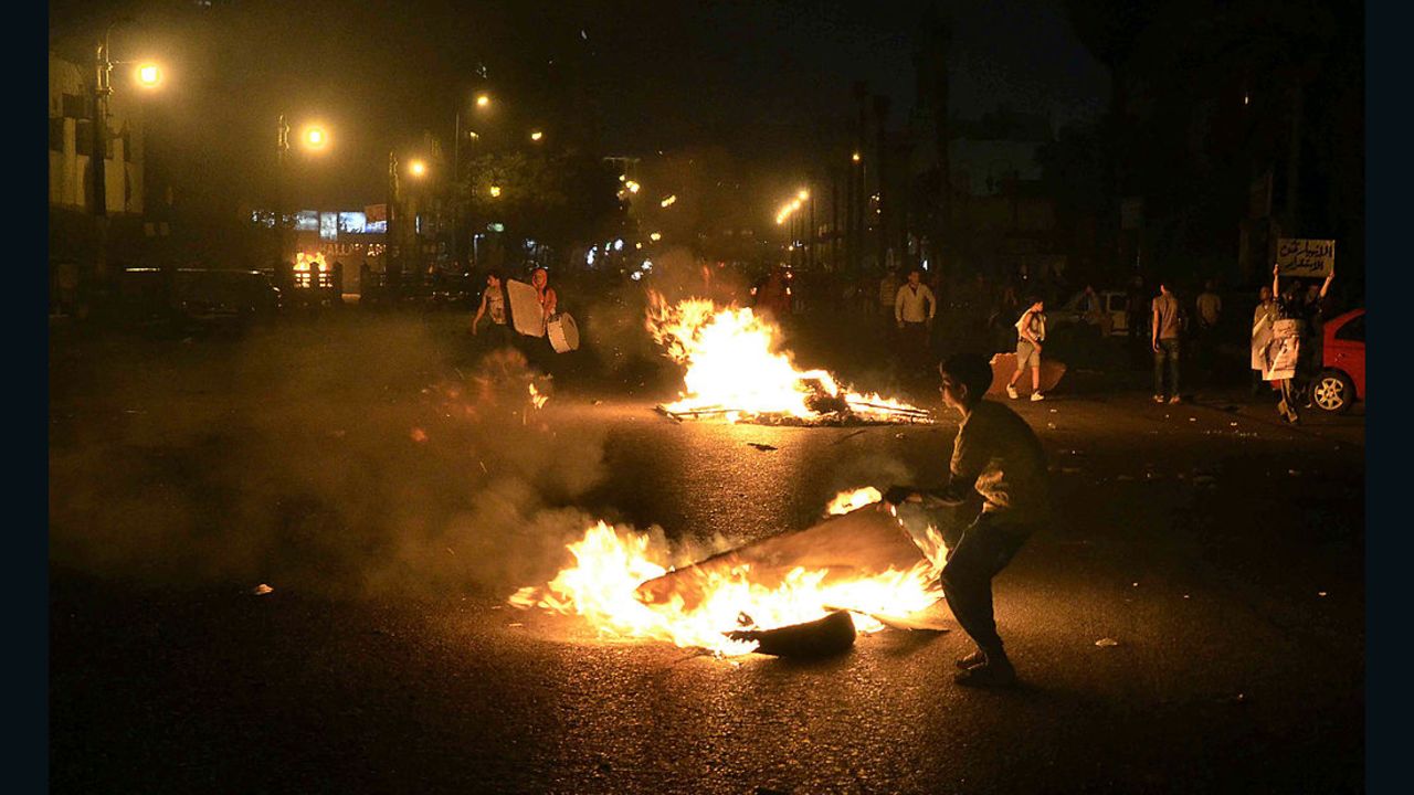 Egyptian anti-government  protesters walk through burning cardboard during clashes between the April 6 movement supporters and police outside the High Court on April 6, 2013 in Cairo.