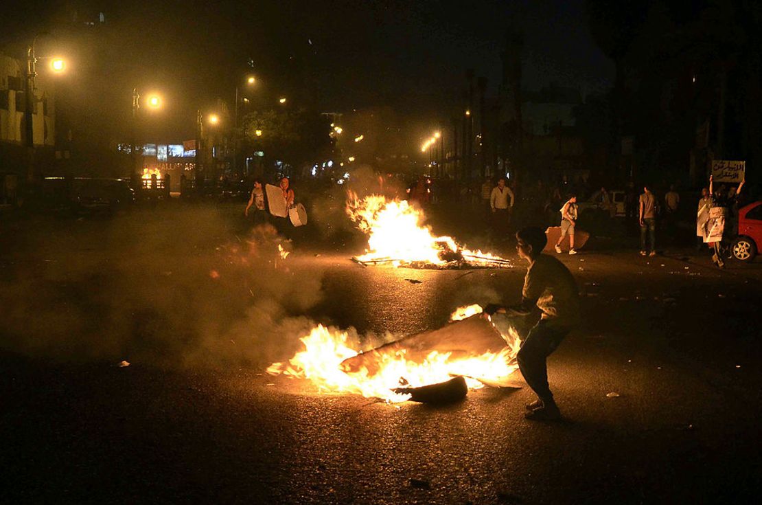 Egyptian anti-government  protesters walk through burning cardboard during clashes between the April 6 movement supporters and police outside the High Court on April 6, 2013 in Cairo.