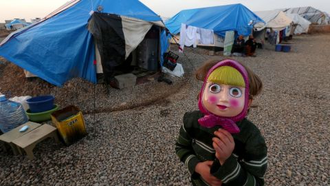 An Iraqi girl who fled the violence in Mosul, Iraq, poses with a mask on New Year's Eve at the Hasansham camp in northern Iraq.