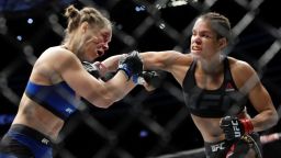 Amanda Nunes, right, connects with Ronda Rousey in the first round of their women's bantamweight championship mixed martial arts bout at UFC 207, Friday, Dec. 30, 2016, in Las Vegas. Nunes won the fight after it was stopped in the first round. (AP Photo/John Locher)