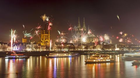 Fireworks illuminate the night sky over Cologne Cathedral and the Rhine River during New Year's Eve celebrations in Cologne, Germany.