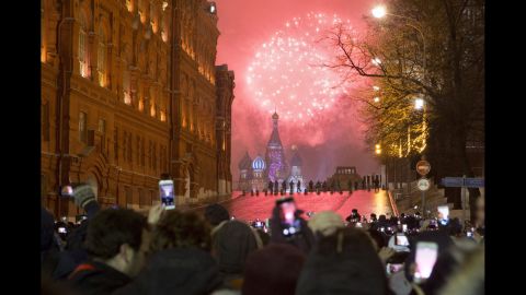 People watch as fireworks explode over the Kremlin in Moscow, Russia.