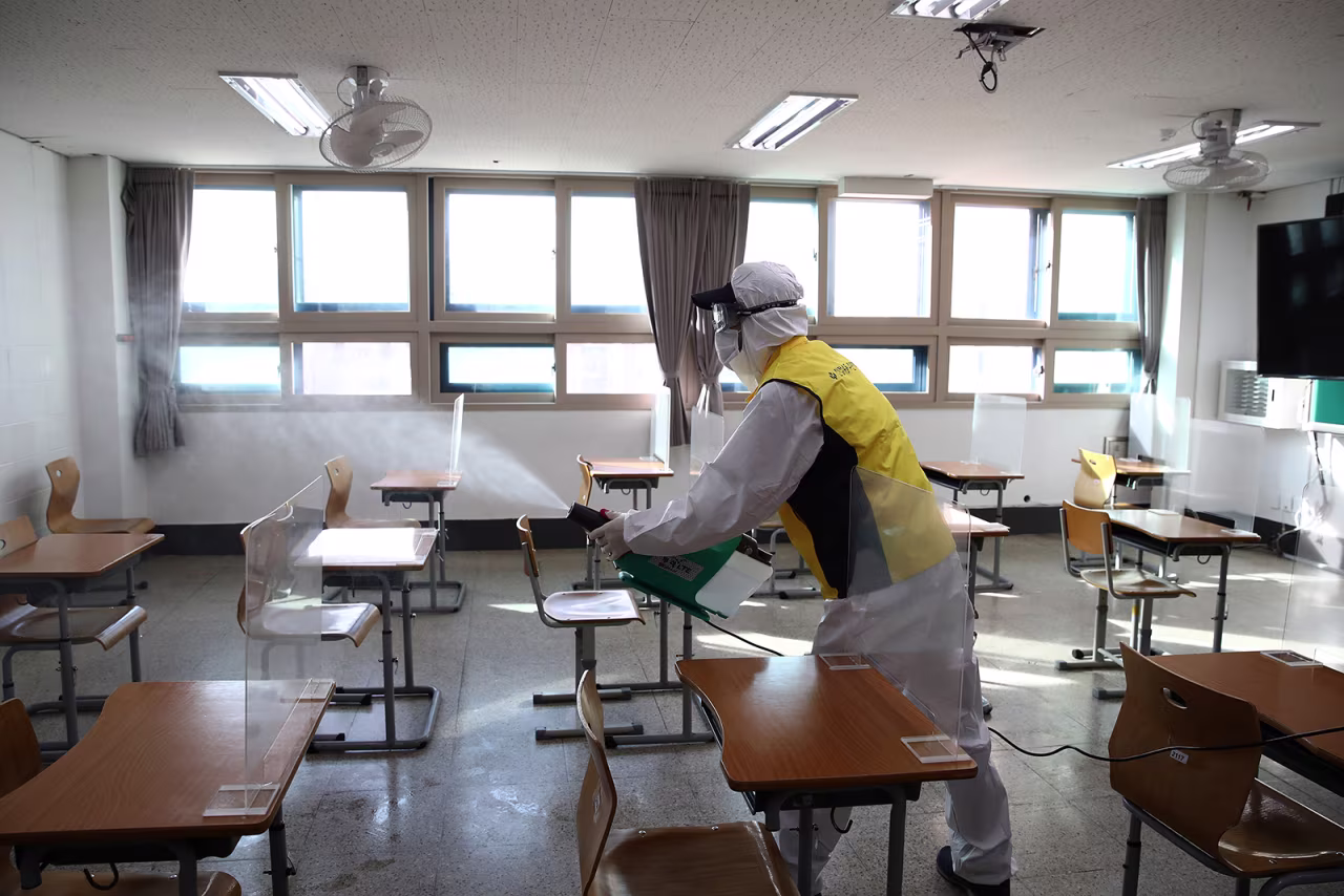 A disinfection worker sprays antiseptic solution in a classroom to prevent the spread of Covid-19 ahead of the annual college scholastic ability test at a YoungSang high school in Seoul on December 1.