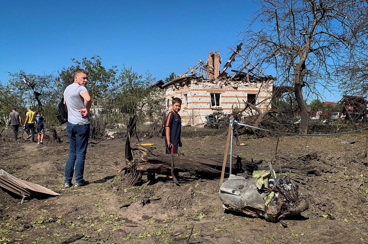 Local residents look at a part of a missile as they stand near residential buildings destroyed during a Russian military strike in the village of Stavchany,  Lviv region, Ukraine on August 15.