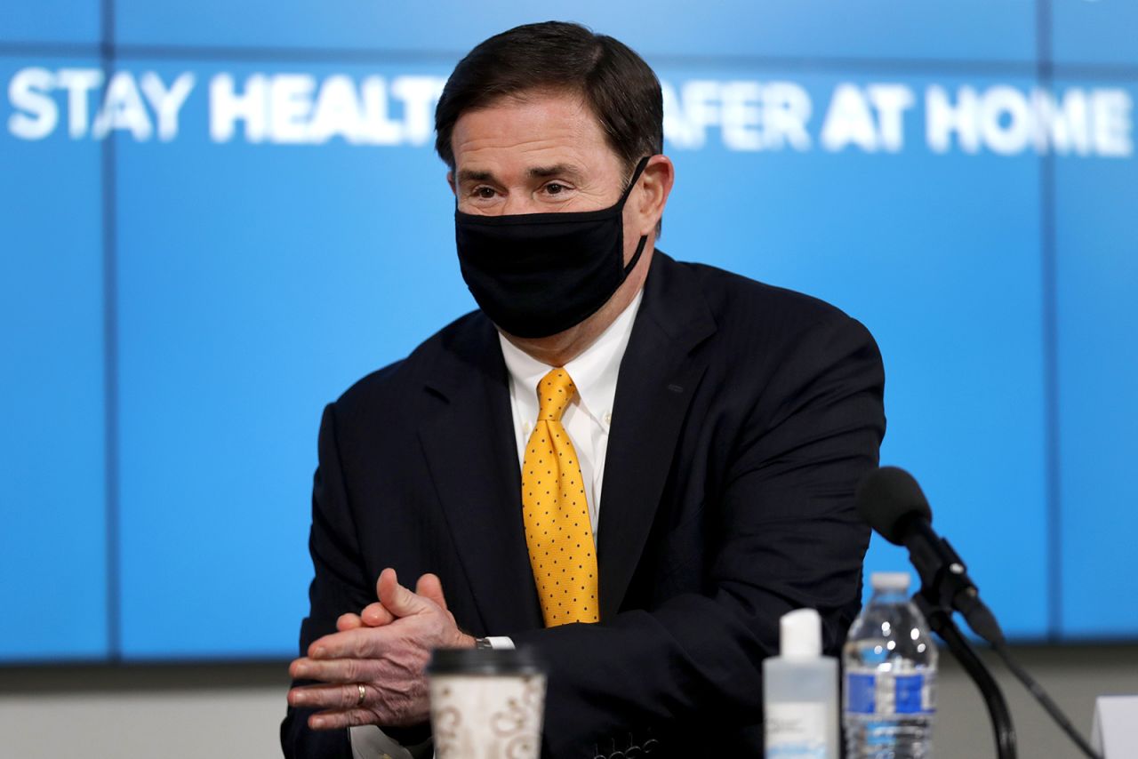 In this July 23, 2020 file photo, Arizona Republican Gov. Doug Ducey applies hand sanitizer prior to giving the latest Arizona coronavirus update during a news conference in Phoenix. 