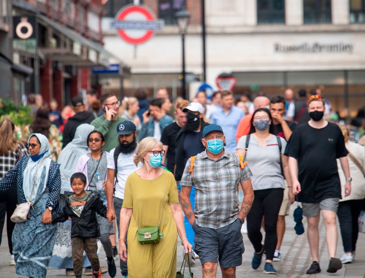 Pedestrians wear face masks while walking down a street in London, on July 4. 