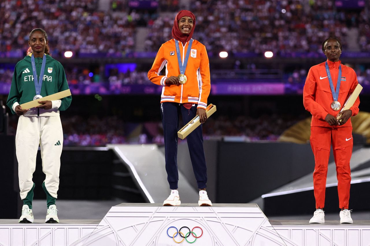 Sifan Hassan of the Netherlands, center, receives her gold medal for the women's marathon alongside silver medalist Ethiopian Tigst Assefa, left, and bronze winner Hellen Obiri of Kenya, right. 