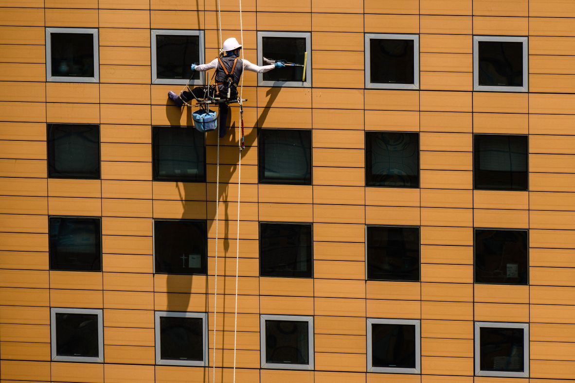 A window cleaner uses a squeegee on a commercial building in Seoul, South Korea, on Monday, June 23.