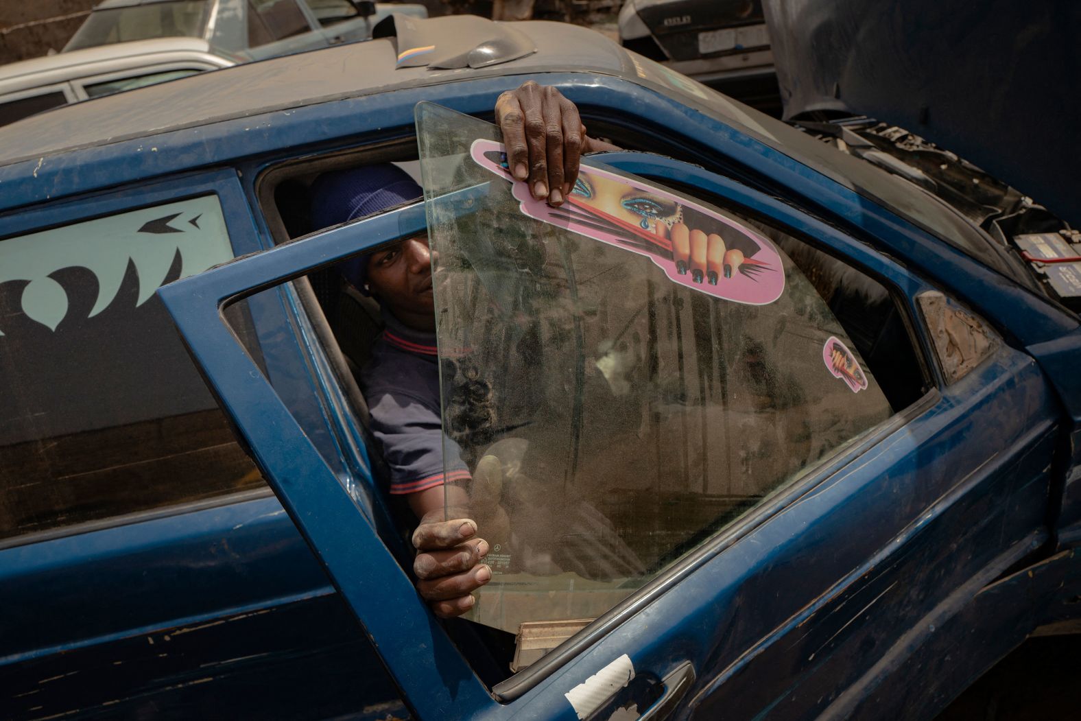 A mechanic places the window of a Mercedes-Benz into the door at a garage in Nouakchott, Mauritania, on Monday, July 8.