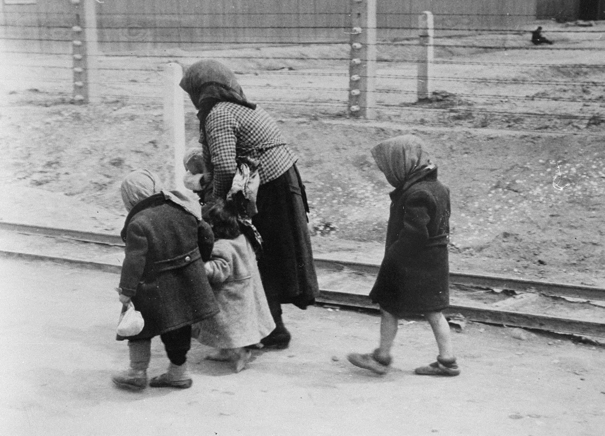 A Jewish woman walks toward the gas chambers with three young children and a baby in her arms in May 1944.