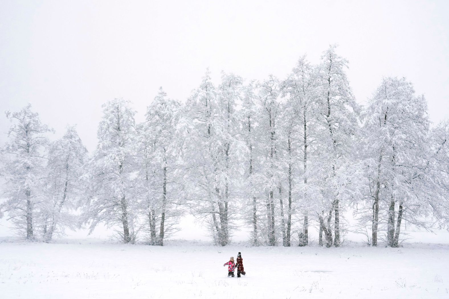 Children walk across a snowy meadow near Wernigerode, Germany, on Thursday, January 9.