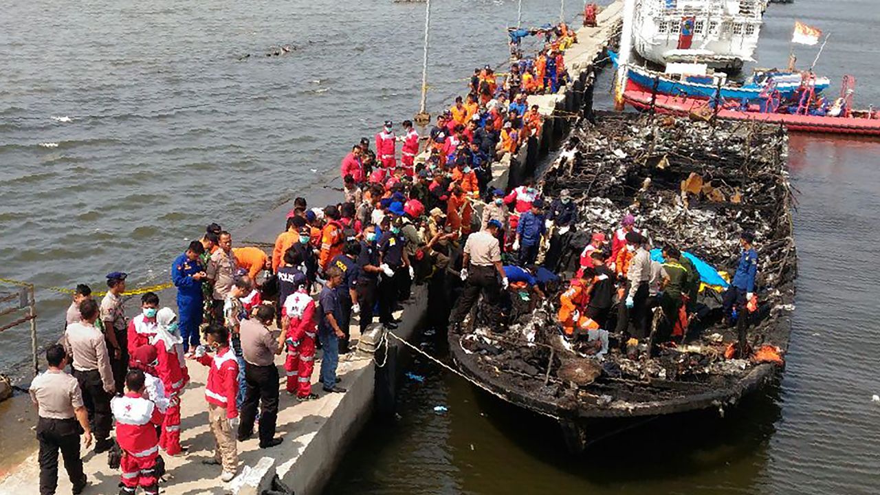 Rescuers search the charred passenger boat.