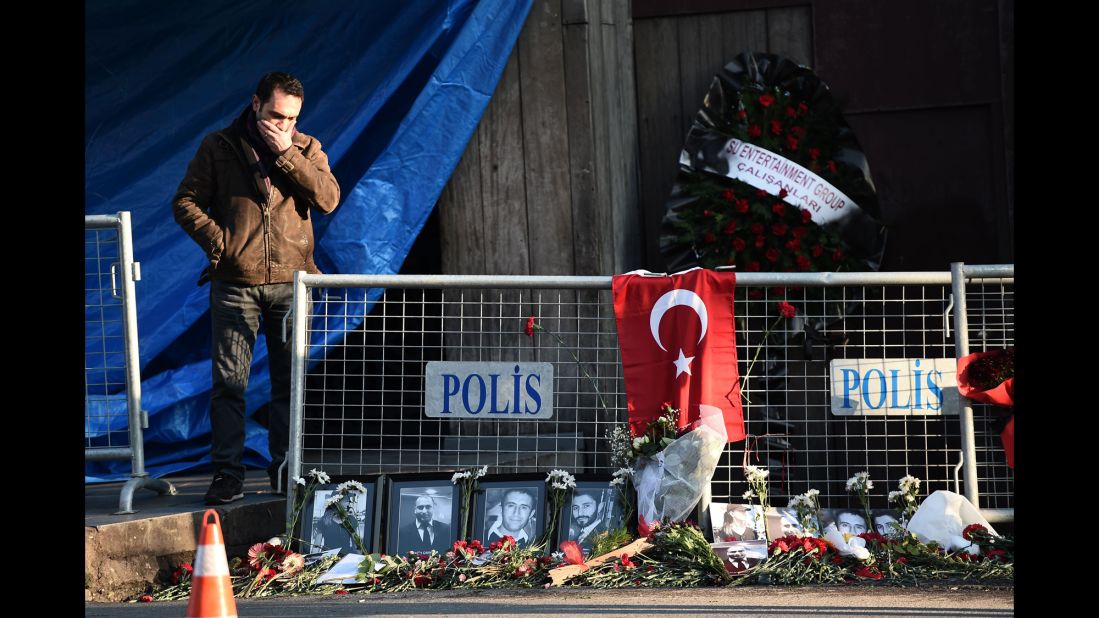 A friend of someone killed in the attack reacts near victims' pictures outside the nightclub on January 2.
