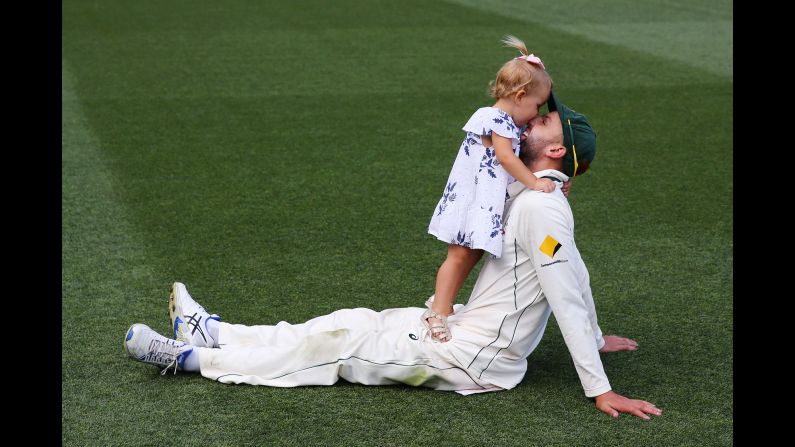 Cricket player Nathan Lyon celebrates with his daughter Friday, December 30, after Australia defeated Pakistan in a Test match in Melbourne.