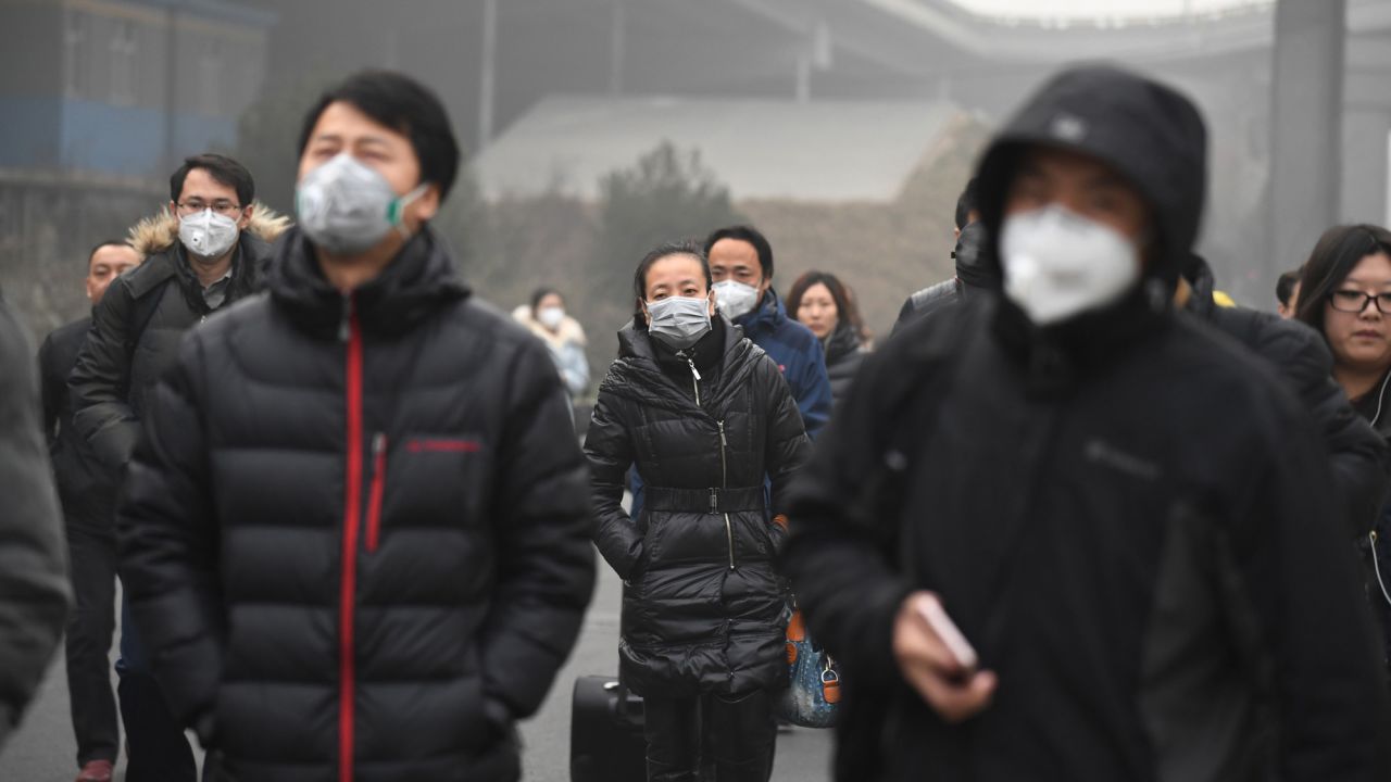 Commuters wear masks on a polluted day in Beijing on December 20. Hundreds of flights were canceled and road and rail transport ground to a halt under the low visibility.