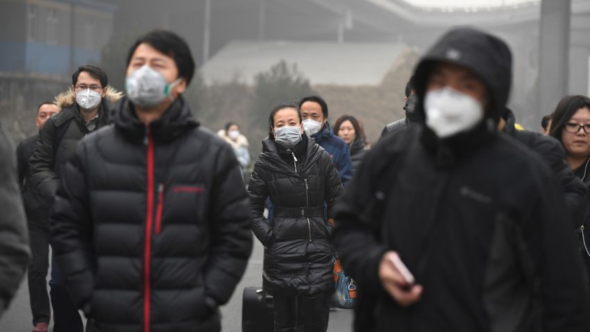 Commuters wear masks on a polluted day in Beijing on December 20, 2016. Heavy smog suffocated northeast China for a fifth day on December 20, with hundreds of flights cancelled and road and rail transport grinding to a halt under the low visibility conditions. / AFP / Greg Baker        (Photo credit should read GREG BAKER/AFP/Getty Images)