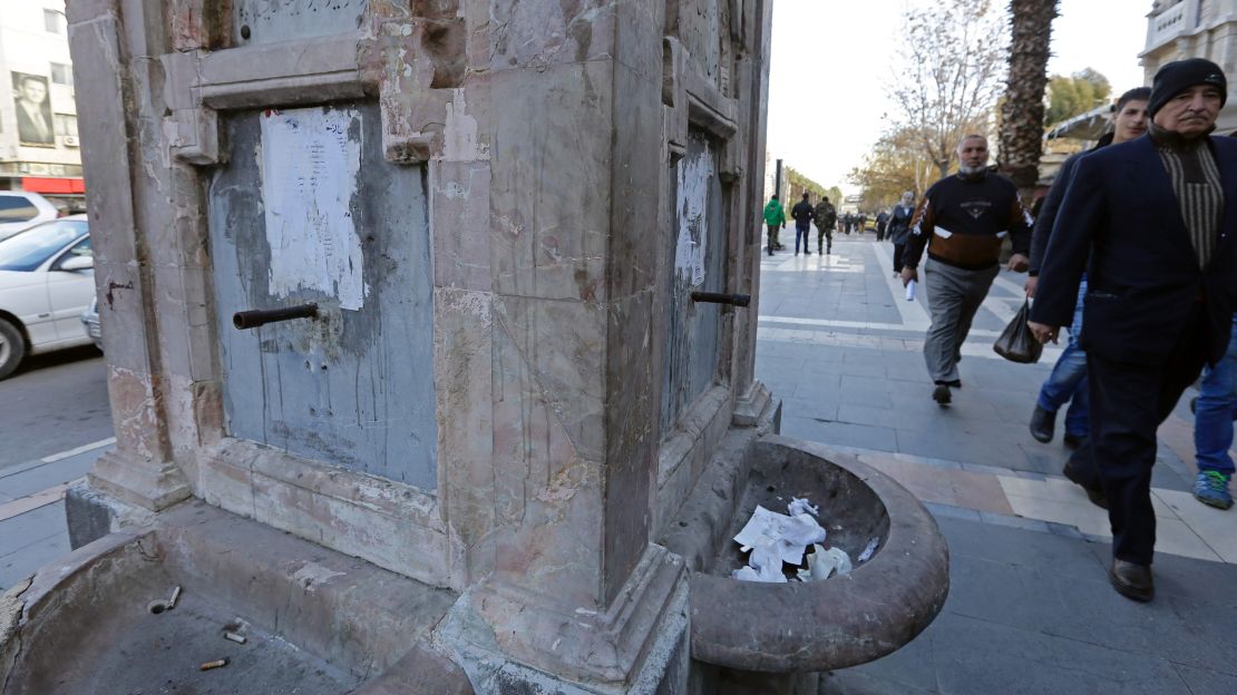 Residents walk past a drinking fountain that has run dry.