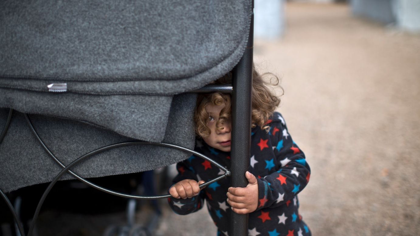 Moustafa Abdulrahman, a 2-year-old Syrian refugee, peeks outside his family's shelter at the Ritsona camp in Greece on Thursday, January 5. More than 60,000 migrants are stranded in Greece after a series of Balkan border closures and a European Union deal with Turkey.
