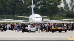 People stand on the tarmac at the Fort Lauderdale-Hollywood International Airport after a lone shooter opened fire inside the terminal, Friday, January 6, in Fort Lauderdale, Florida.  