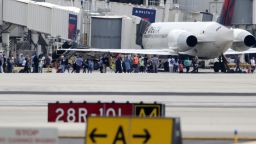 People stand on the tarmac at the Fort Lauderdale-Hollywood International Airport after a shooter opened fire inside the terminal, killing several people and wounding others before being taken into custody, Friday, January 6 in Fort Lauderdale, Florida. 