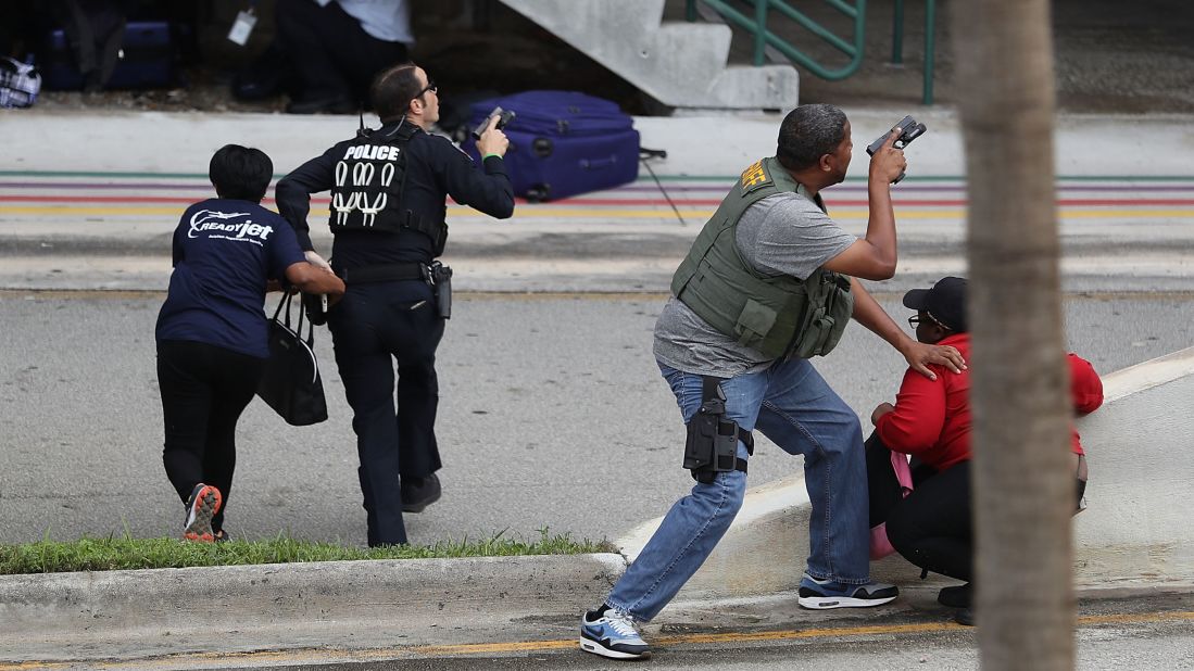 Police assist people seeking cover outside Terminal 2 at the Fort Lauderdale airport. 