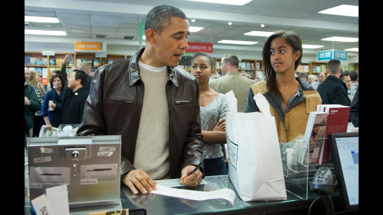 Obama, with Sasha, center, and Malia, pays for a purchase at the Politics & Prose bookstore in northwest Washington in November 2013. 