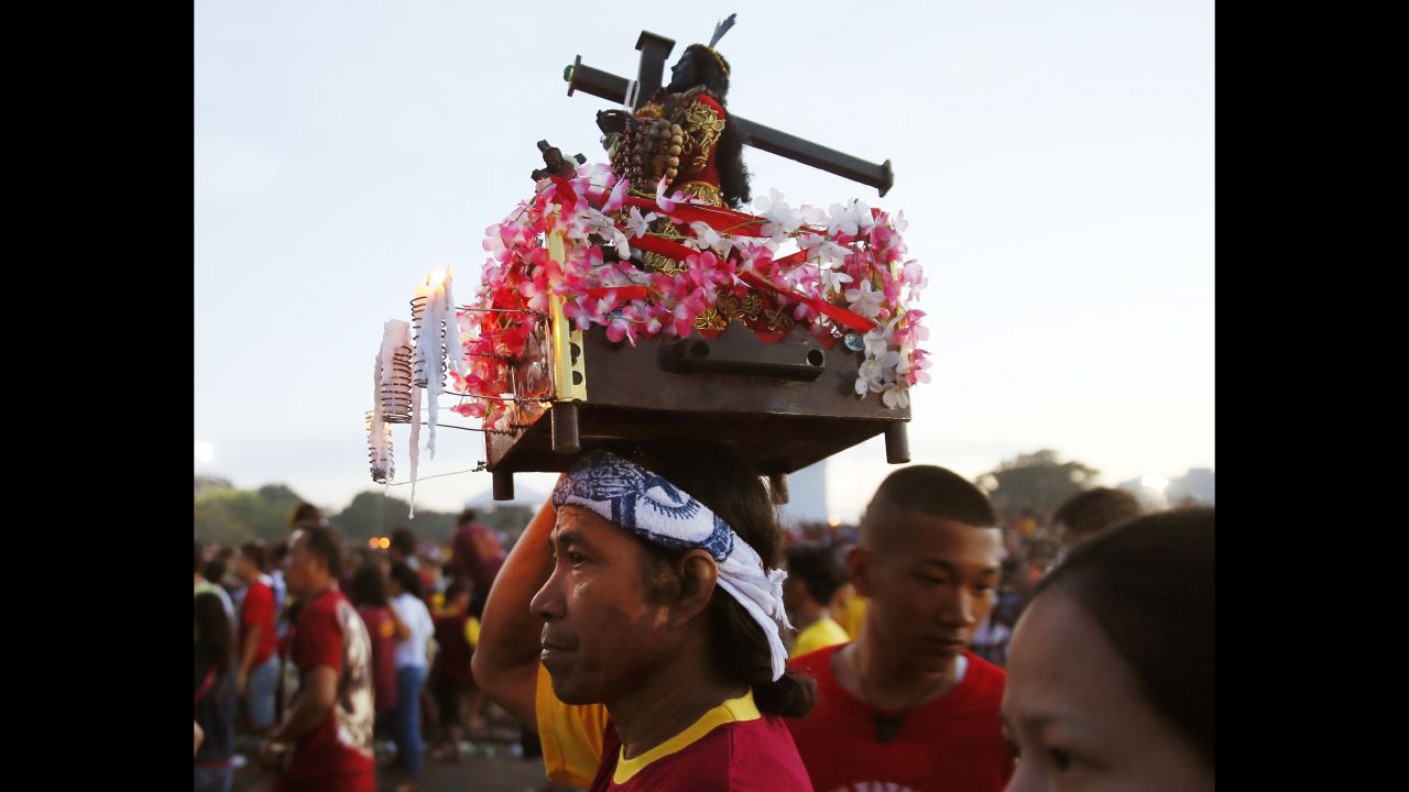 A devotee carries a replica of the Black Nazarene. The raucous celebration drew tens of thousands of devotees in a barefoot procession for several hours around Manila streets.