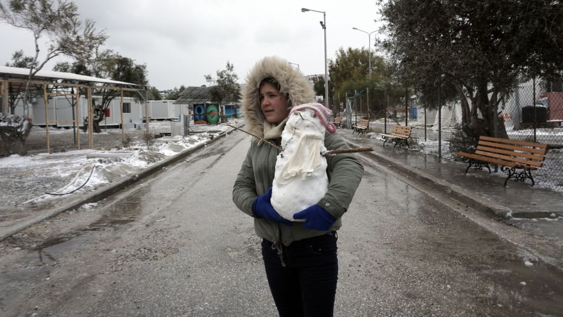 A girl holds a snowman at the Kara Tepe camp on the Greek island of Lesbos following heavy snow.