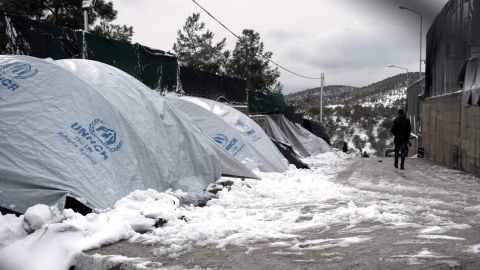 An asylum seeker walks next to snow-covered tents at the Moria refugee camp.