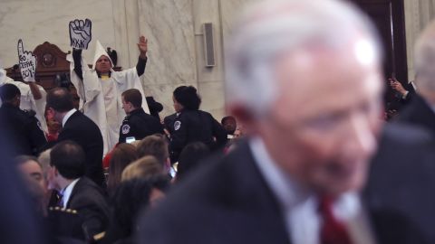 Protestors are seen behind Attorney General-designate, Sen. Jeff Sessions, R-Ala., as he arrives on Capitol Hill in Washington, Tuesday, Jan. 10, 2017, to testify at his confirmation hearing before the Senate Judiciary Committee. (AP Photo/Andrew Harnik)