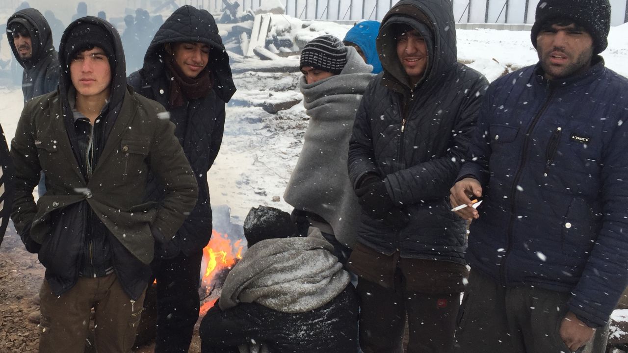 Migrants huddle around a fire in the freezing conditions.