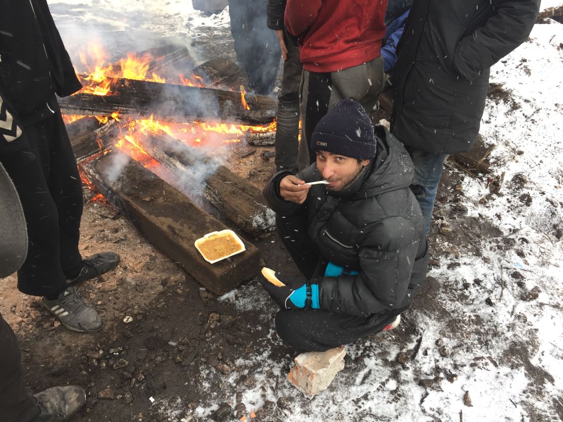 After they receive food from aid agencies once a day, migrants warm it up by the open fires they light by burning, wood, scraps, or any other material they can get their hands on.