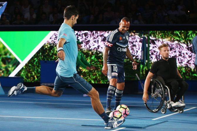 The tennis star has a go at football with Australian legend Archie Thompson (center) looking on. Thompson earned over 50 caps for Australia.