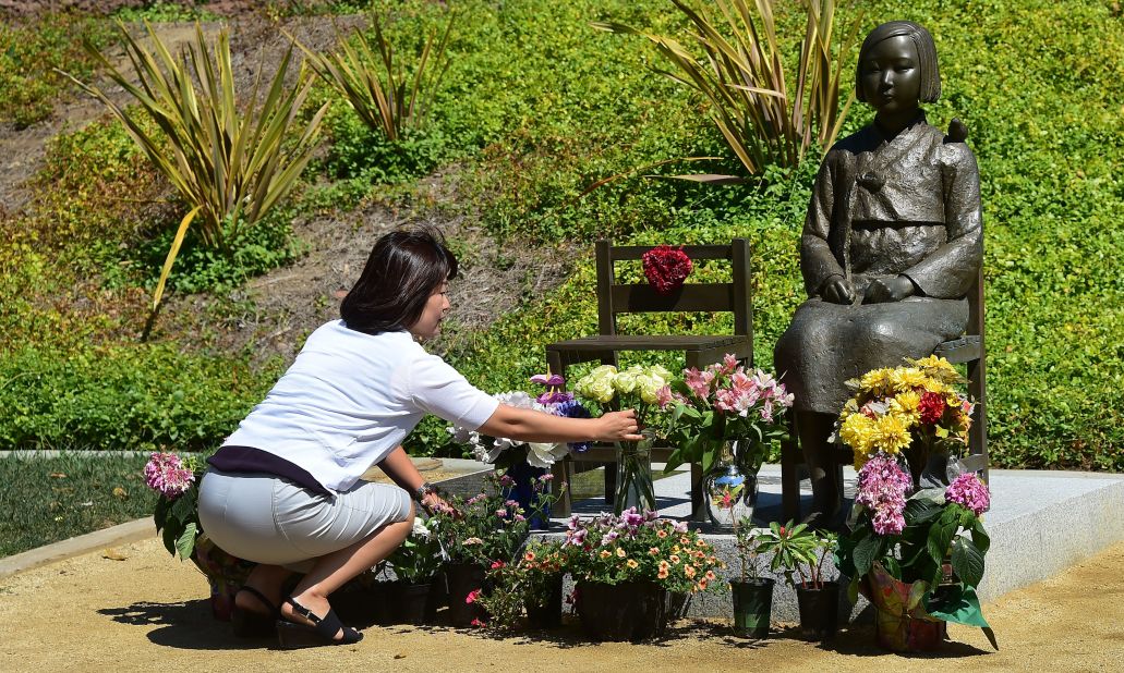 A woman arranges flowers in front of a "comfort woman" statue in Glendale, California. 