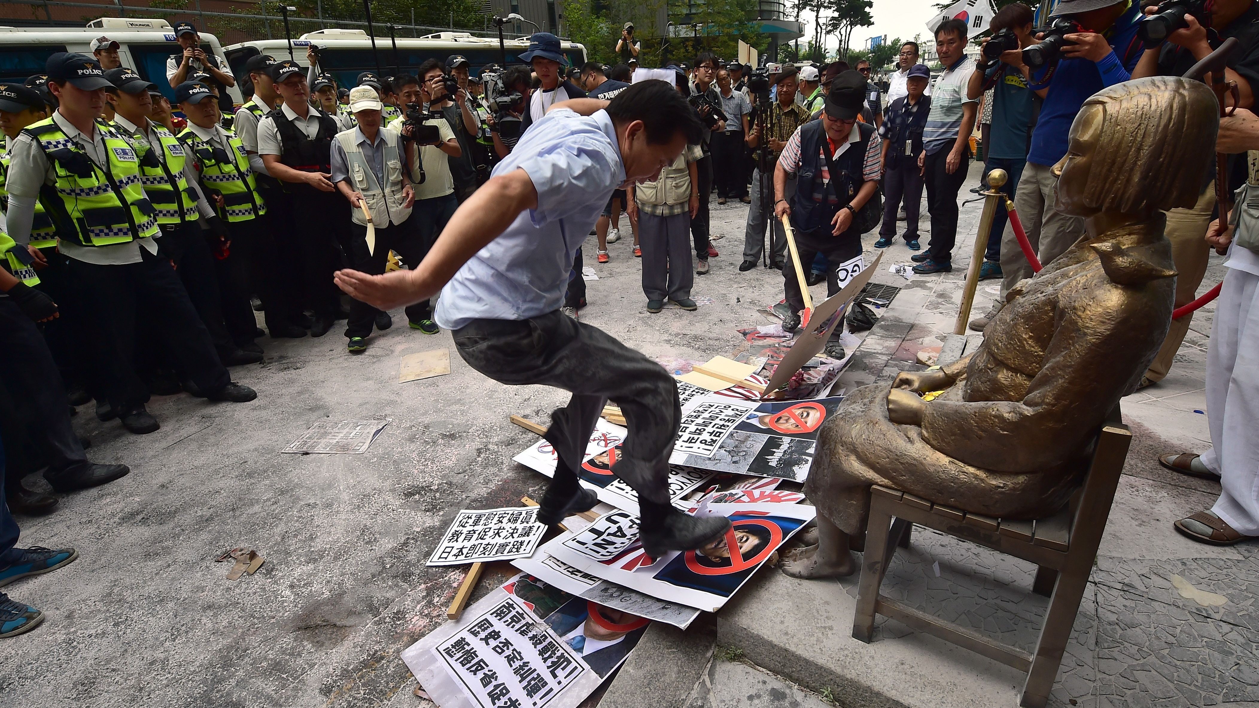 A protester tramples photos of Japanese Shinzo Abe in front of a state memorializing Korean WWII sex slaves, also known as "comfort women." 