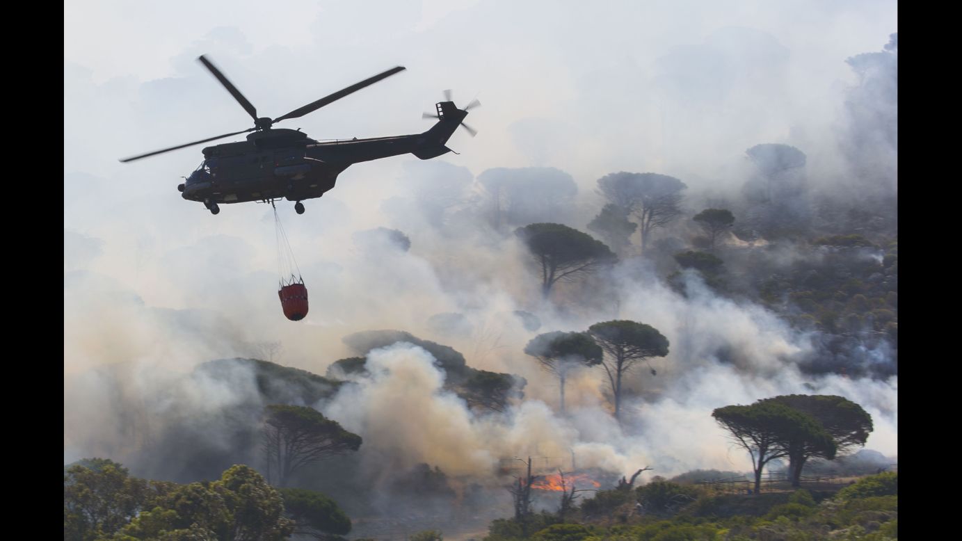 A firefighting helicopter flies over a massive wildfire in Cape Town, South Africa, on Wednesday, January 11.
