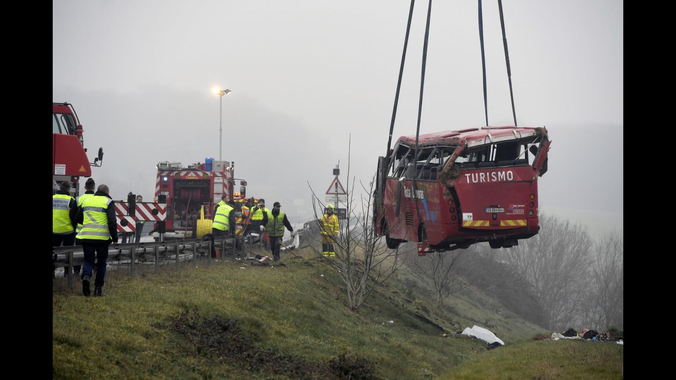 Rescue workers stand near a bus that crashed off a highway near Charolles, France, on Sunday, January 8. Four Portuguese tourists were killed in the crash, authorities said. 