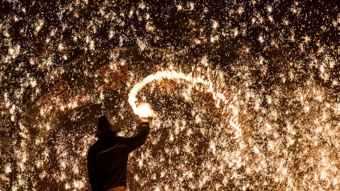 A Chinese blacksmith throws molten metal against a cold stone wall to create sparks, during the Lunar New Year celebration in Nuanquan, Hebei province on February 11, 2016.  For over 300 years, the village has carried out the tradition of spraying molten iron at 1,300 degrees Celsius against a cold concrete wall to form spark-like fireworks during the Chinese New Year celebration, according to the organizer.   AFP PHOTO / JOHANNES EISELE / AFP / JOHANNES EISELE        (Photo credit should read JOHANNES EISELE/AFP/Getty Images)