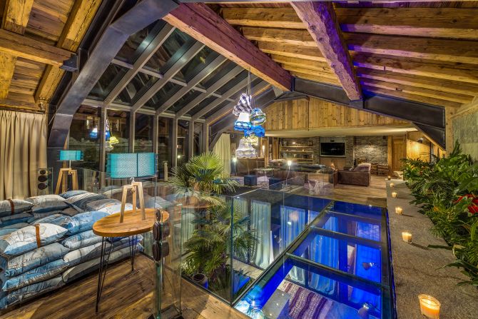 <strong>Chalet Husky, Val d'Isere (France):</strong> Chalet Husky features a vast open-plan living space. Its bar and dining area is linked with a sofa-surrounded open fireplace by a glass walkway over an indoor atrium garden.
