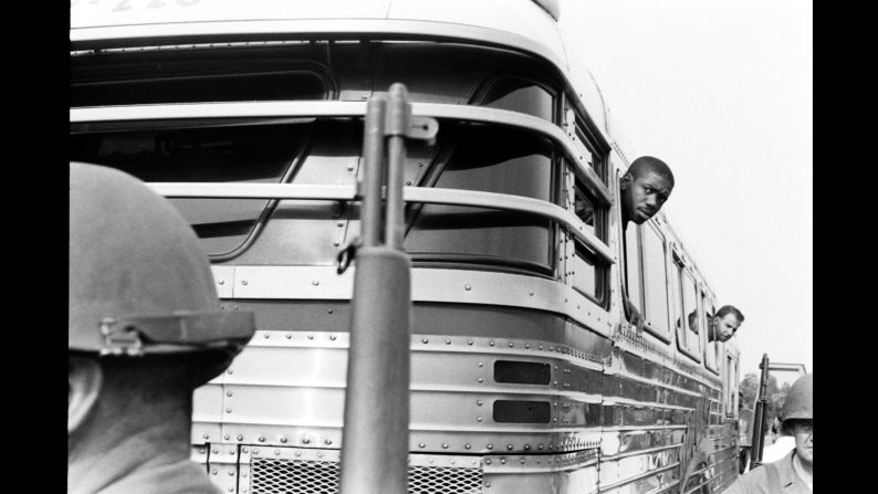 Freedom Riders look out from bus windows during a stop.