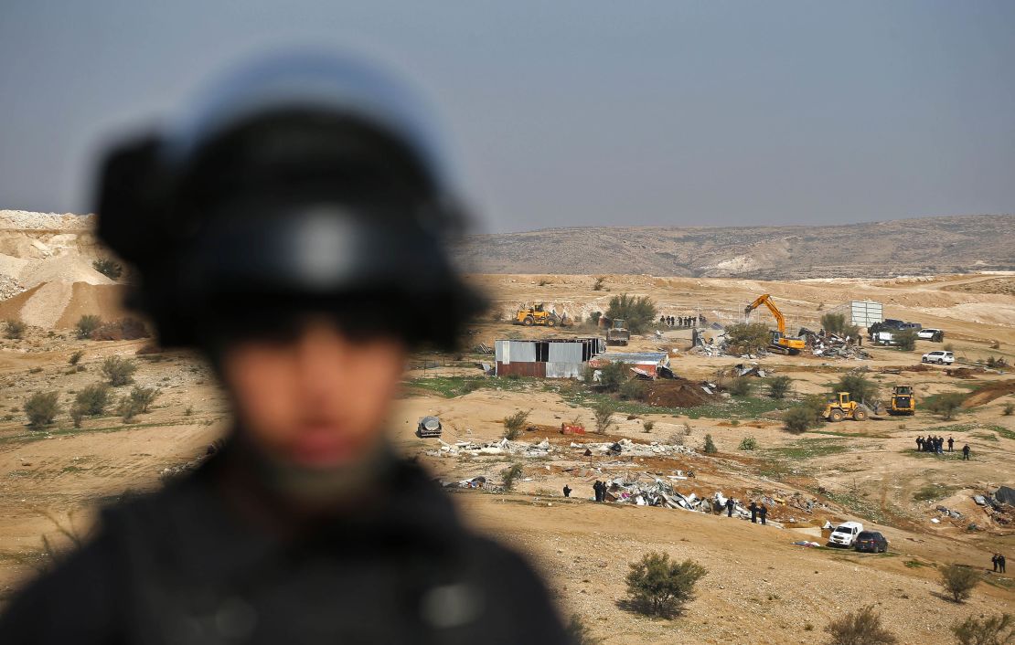 An Israeli officer on guard as bulldozers demolish homes in the Bedouin village of Umm al-Hiran.