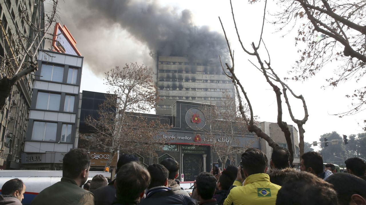 Iranians watch the Plasco building where smoke rises from its windows in central Tehran, Iran, Thursday, Jan. 19, 2017.