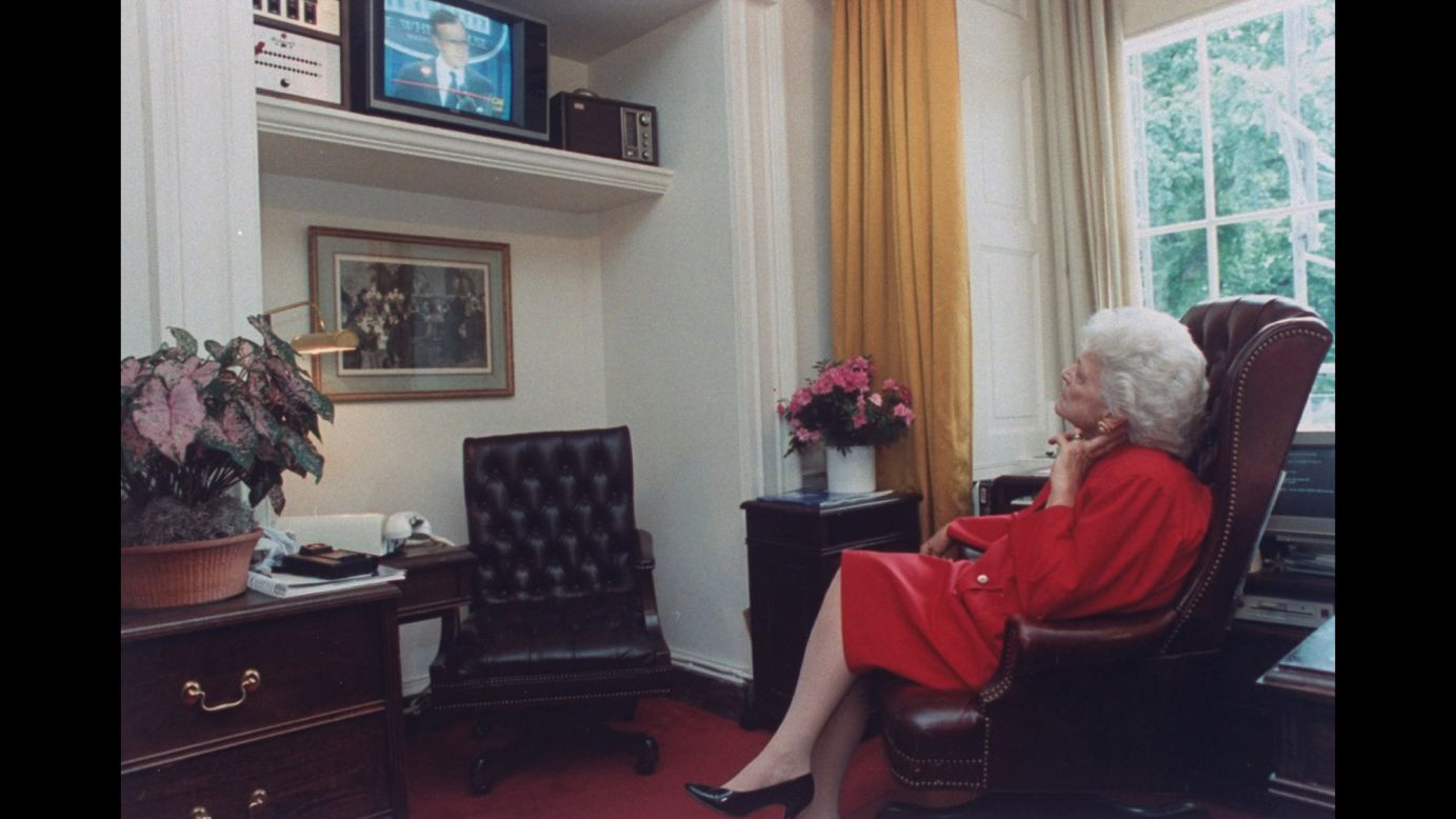 Bush watches her husband from a White House television as he speaks during a news conference.